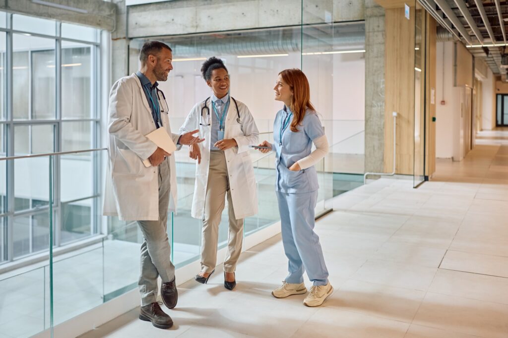 Team of happy healthcare experts talking in hallway of a medical clinic.